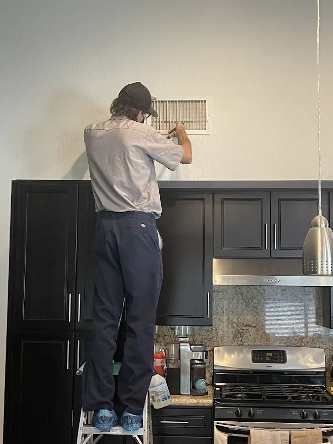 Technician inspecting an air vent during HVAC service in Middle
